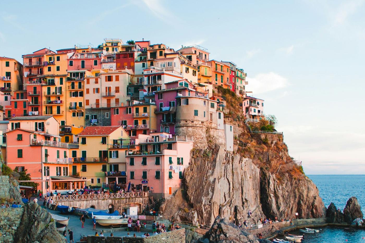 Pastel-coloured village houses on a cliff above the Ligurian Sea in Cinque Terre, Italy